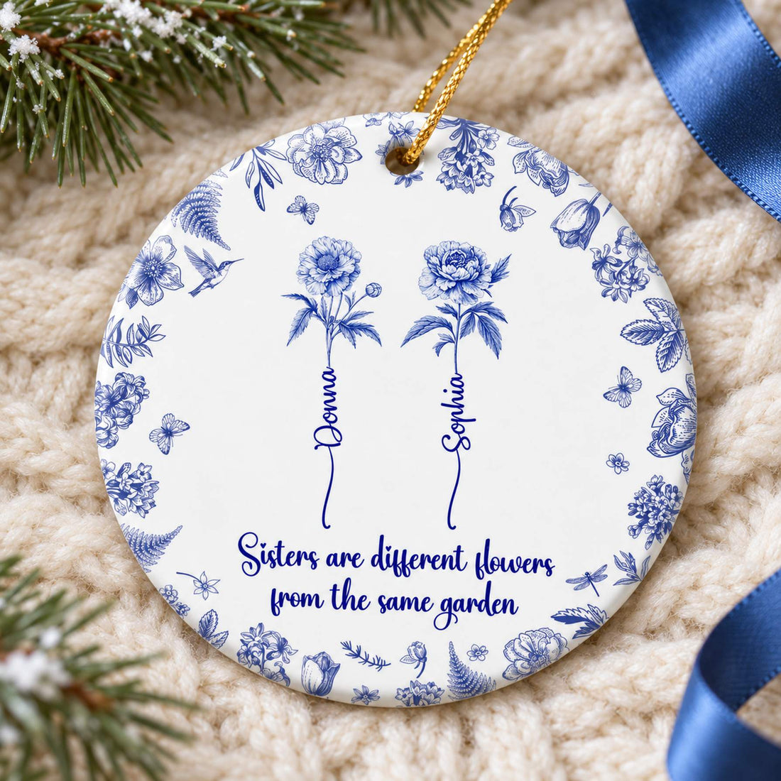 Sisters different flowers ceramic ornament lying flat on a cozy cream knit throw with pine greenery