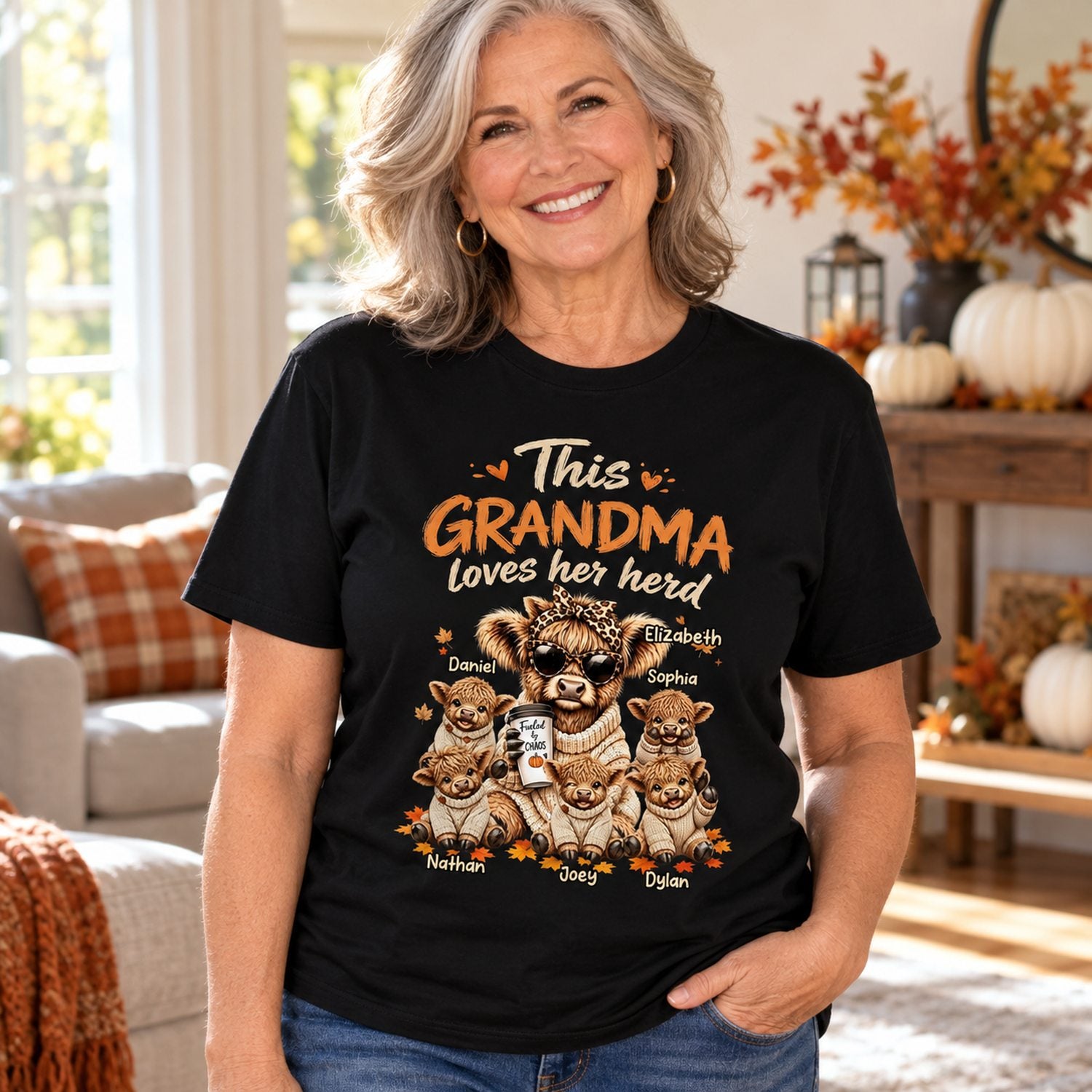 Grandma wearing personalized This Grandma Loves Her Herd fall Highland cow black t-shirt in a bright autumn home