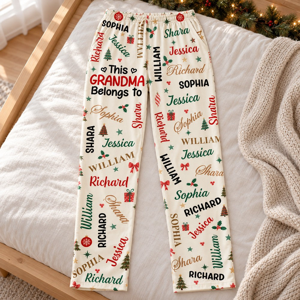 Personalized Grandma Christmas pajama pants laid flat on a wooden surface with holiday greenery