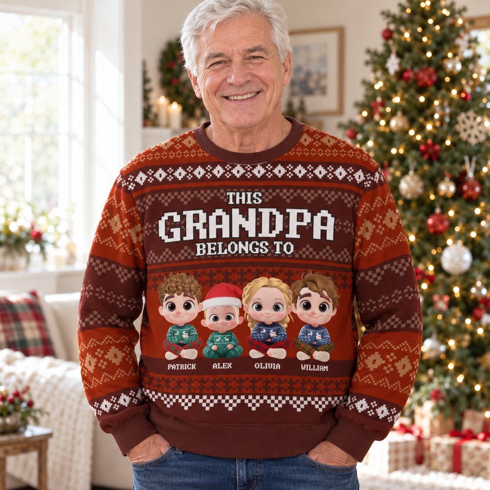 Grandpa wearing personalized This Grandpa Belongs To ugly Christmas sweater in a bright holiday living room