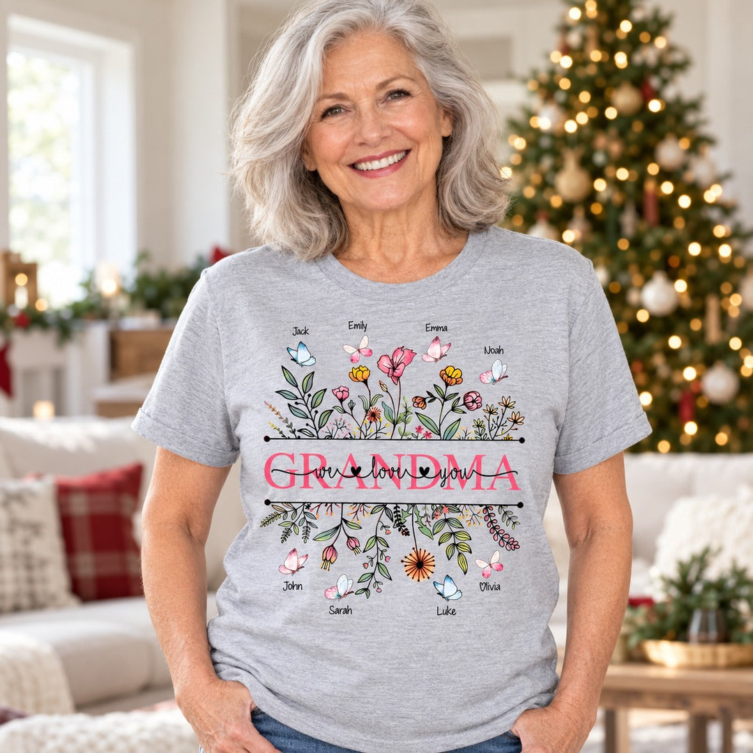 Grandma wearing personalized Wildflower Grandma We Love You grey t-shirt near a Christmas tree