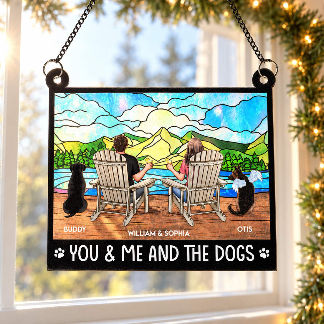You And Me And The Dogs personalized window suncatcher hanging near holiday pine garland