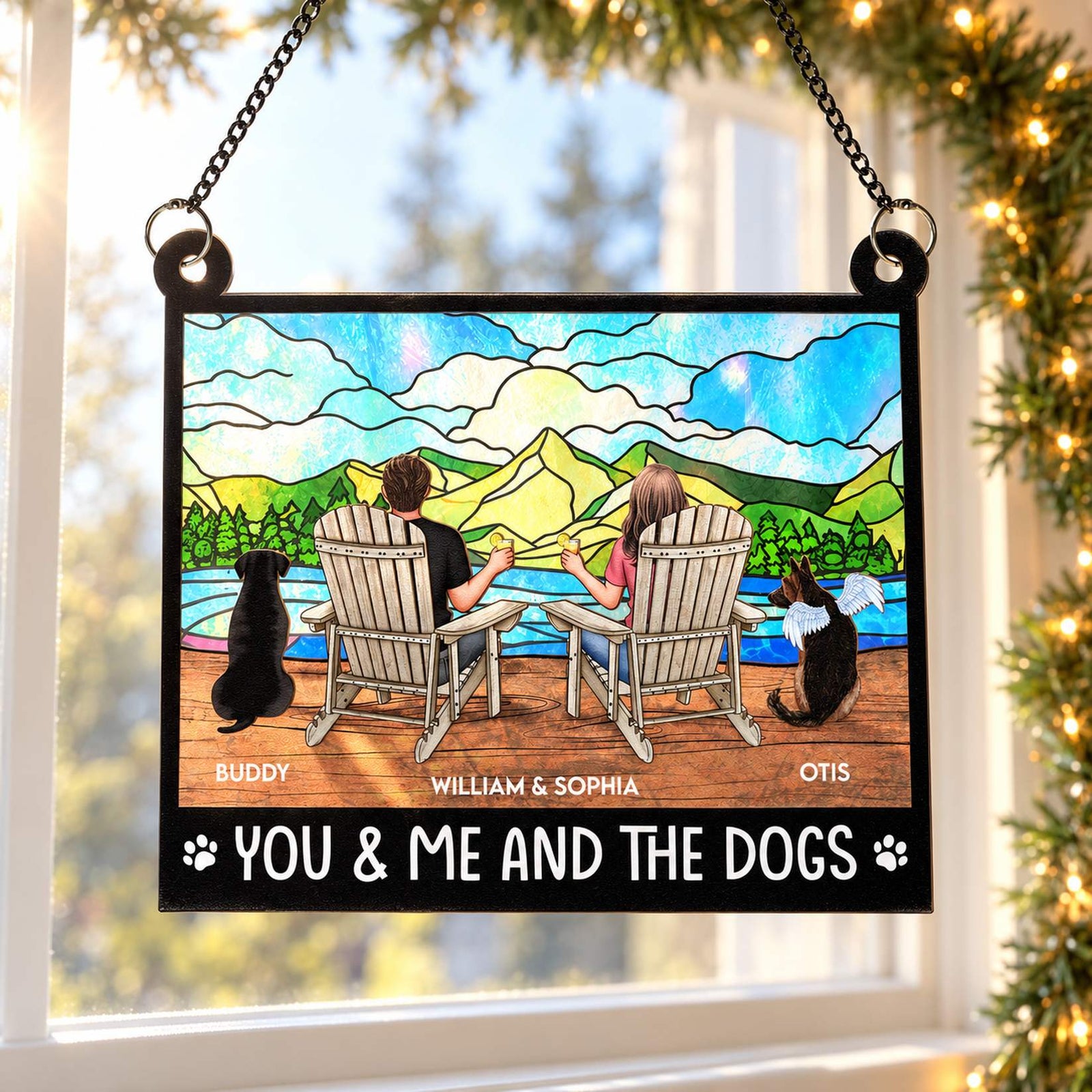 You And Me And The Dogs personalized window suncatcher hanging near holiday pine garland