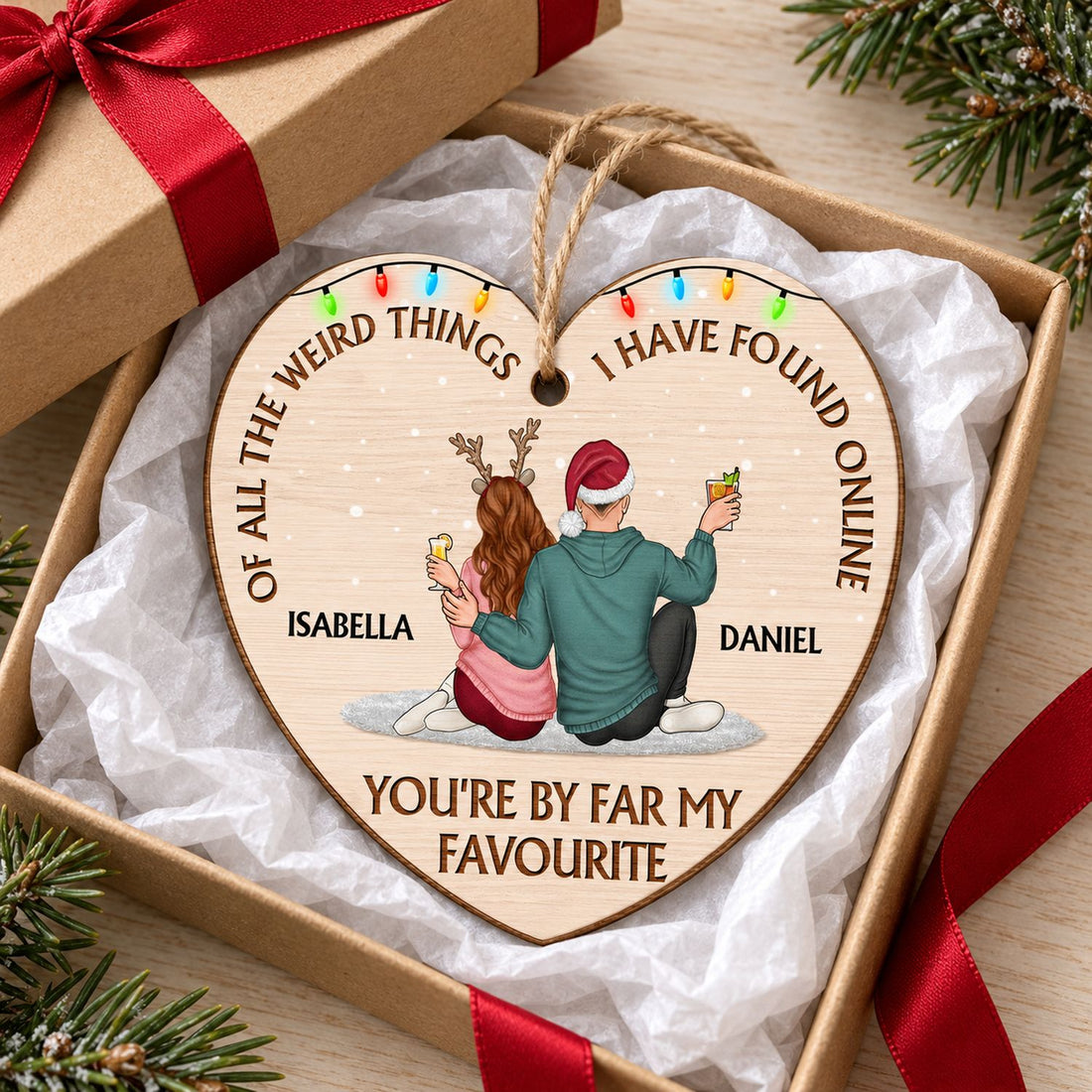 Custom couple wooden heart ornament in an open holiday gift box with red ribbon and pine sprigs