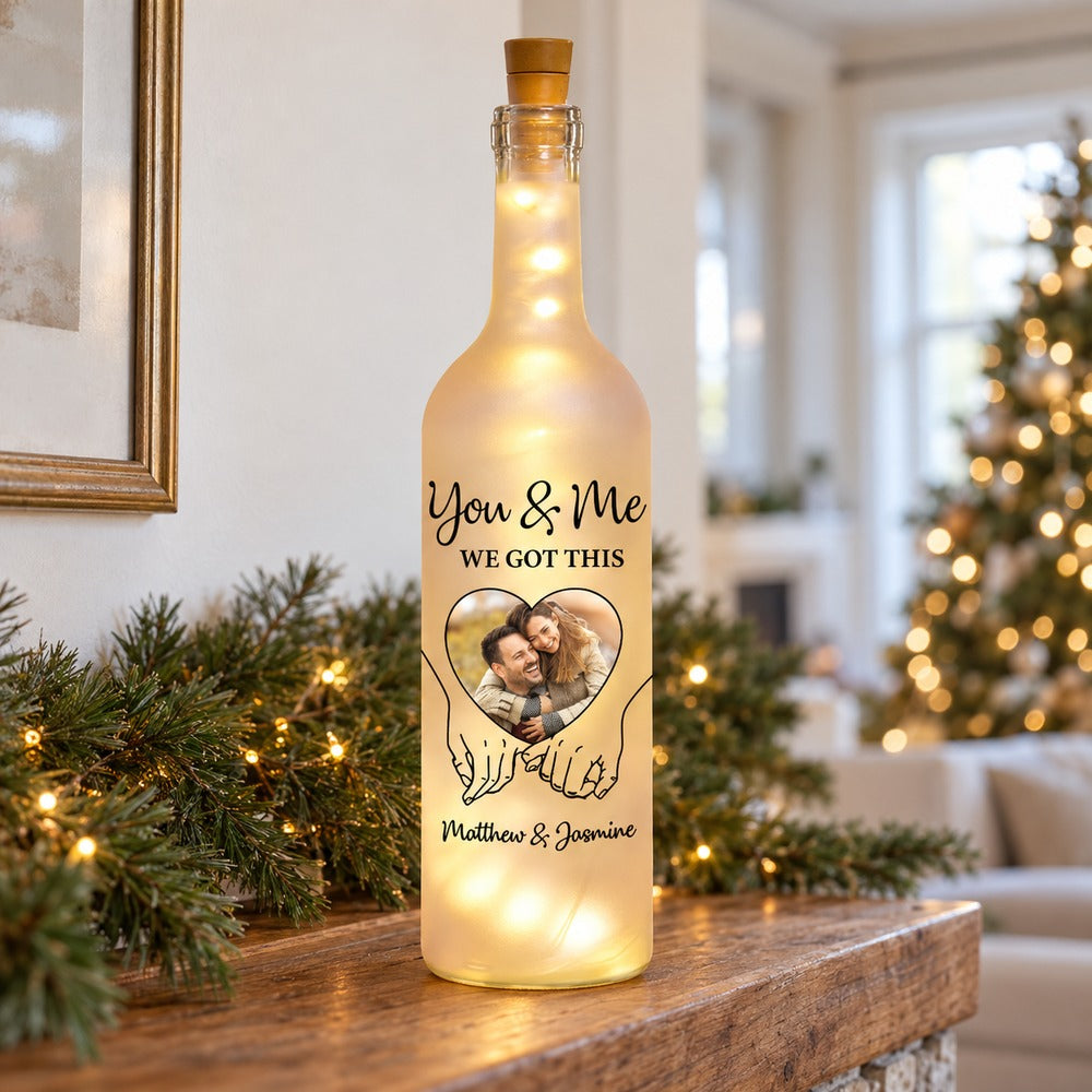 Personalized couple photo bottle light glowing on a holiday mantel with soft pine garland