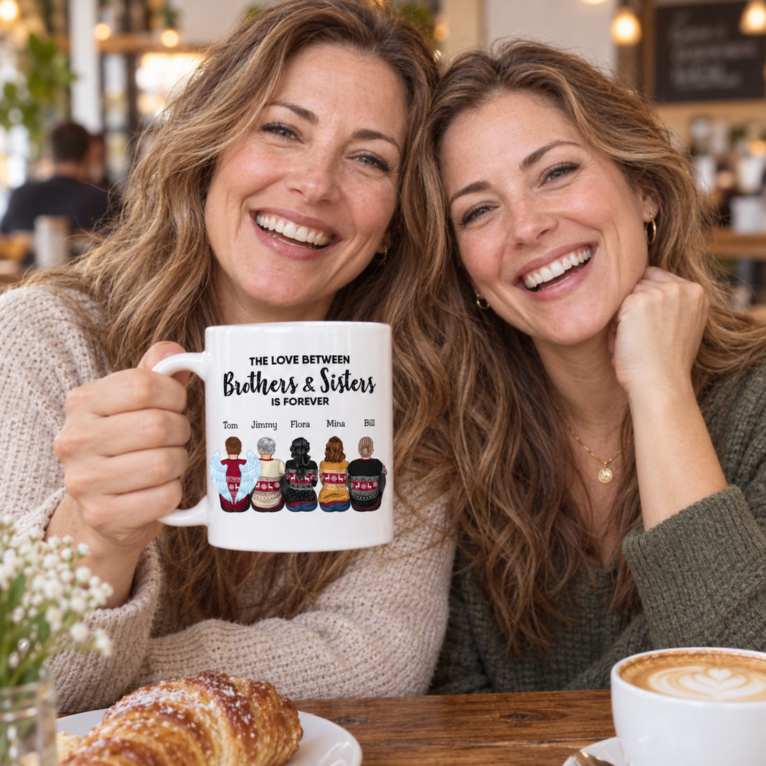 Two sisters laughing together holding a personalized brothers and sisters forever mug at a cafe table