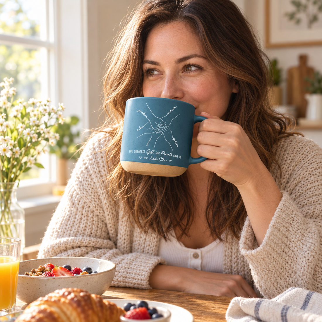 Woman sipping from a personalized blue pottery handprint line art mug at breakfast