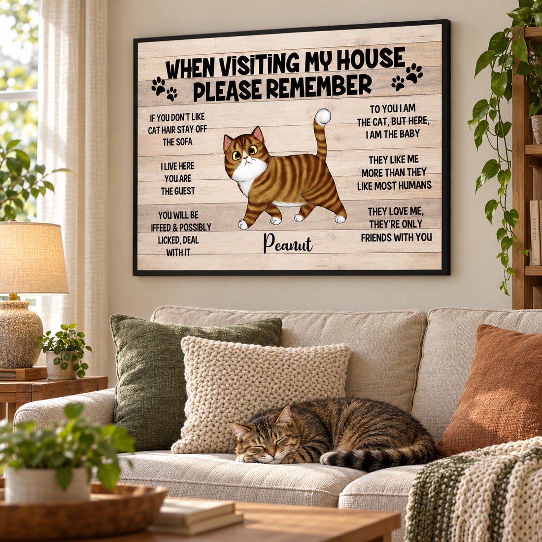Personalized cat house rules canvas print hung above a sofa in a cozy living room with a tabby cat