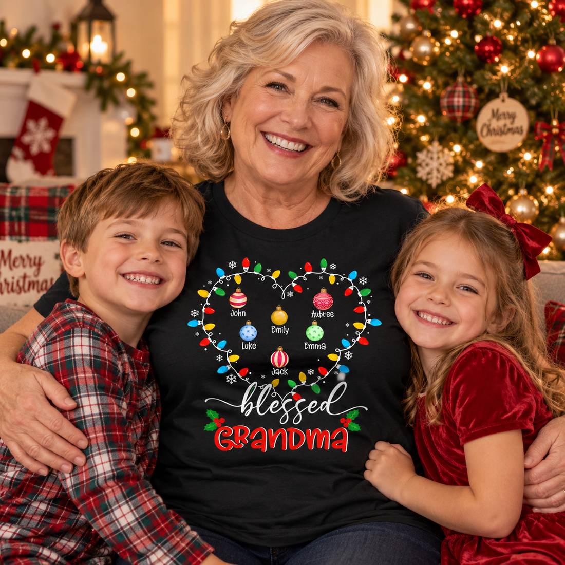 Smiling grandma wearing a black Blessed Grandma heart lights Christmas t-shirt hugging two grandkids by a tree
