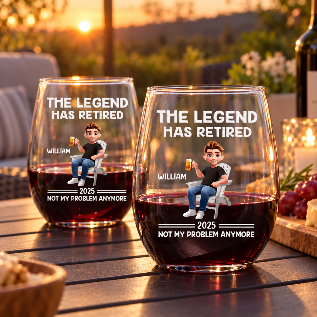 Two personalized The Legend Has Retired wine glasses on a balcony table at sunset