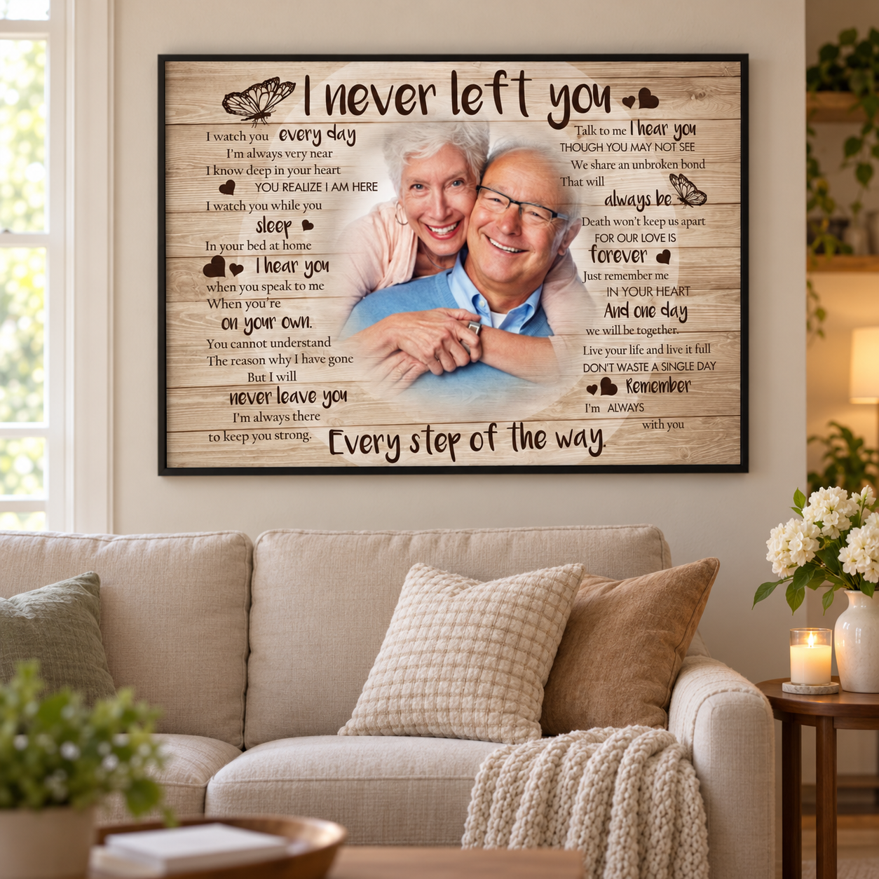 Personalized I Never Left You memorial photo poster above a sofa in a quiet living room with candle and white flowers