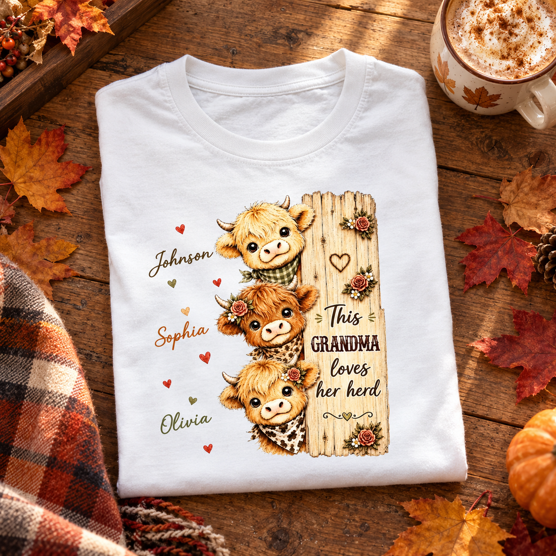 Personalized Highland cow grandma t-shirt folded on a table with fall leaves and a mug