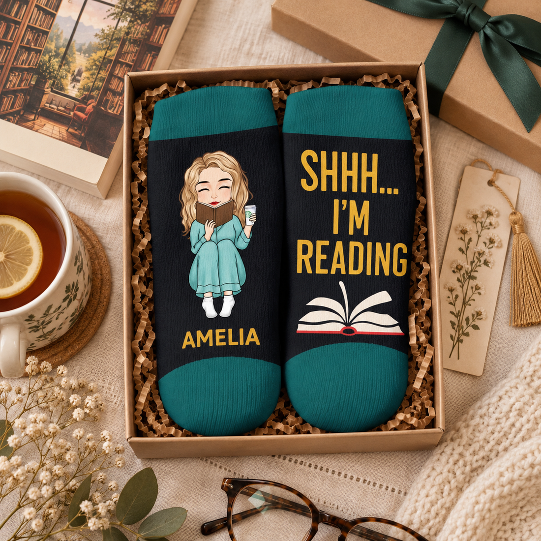 Custom book lover crew socks in a gift box with a paperback and tea, reading gift flat lay