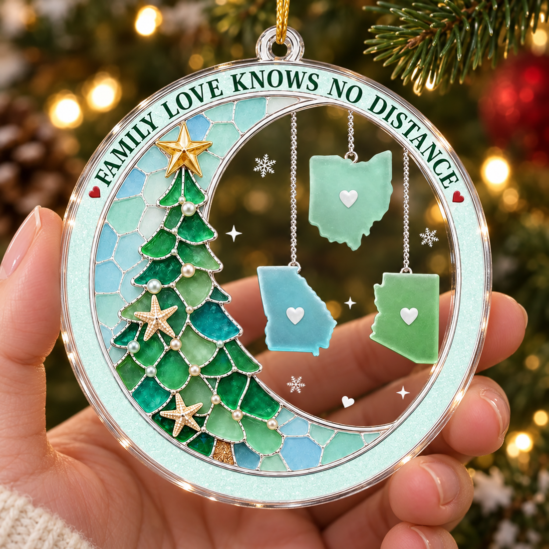 Hand holding a custom acrylic couple ornament, close-up of the clear edge with Christmas lights behind