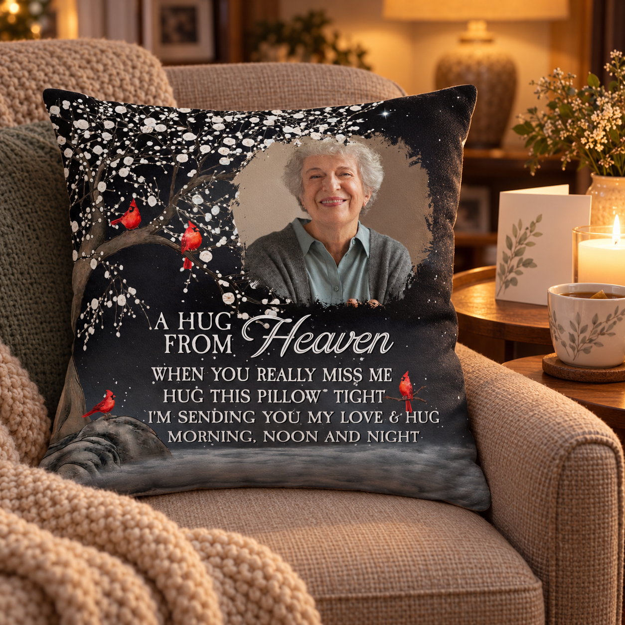 Memorial photo pillow with red cardinals on an armchair beside a candle and sympathy card