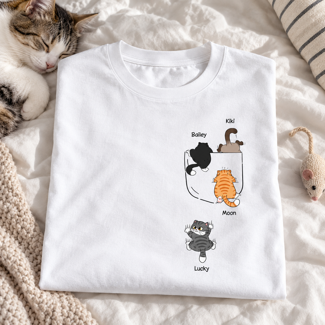 Personalized cute naughty cat pocket t-shirt folded on a bed with a sleeping cat