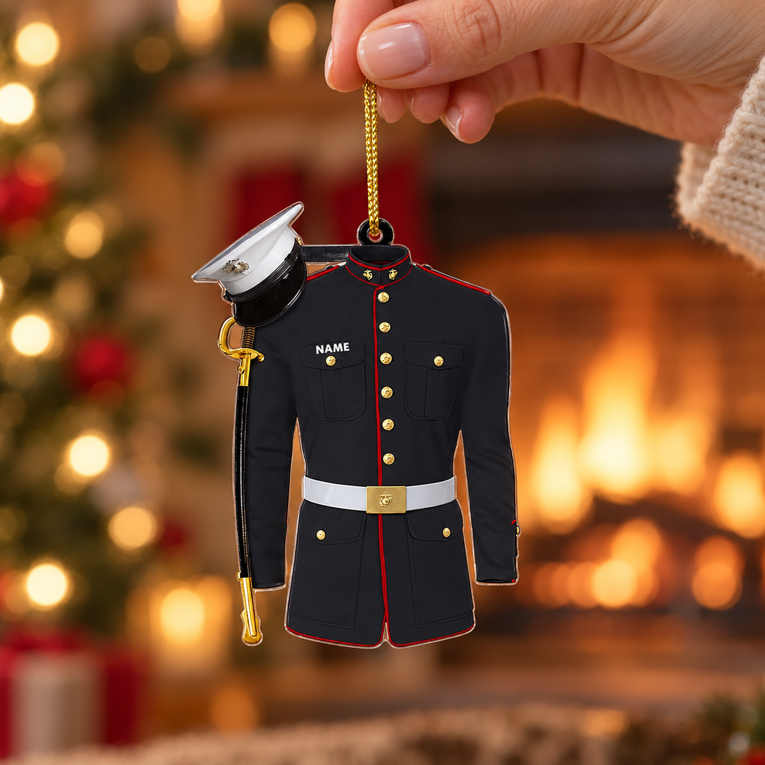 Hand holding a custom Marine dress blues uniform ornament by its gold cord in front of a warm fireplace