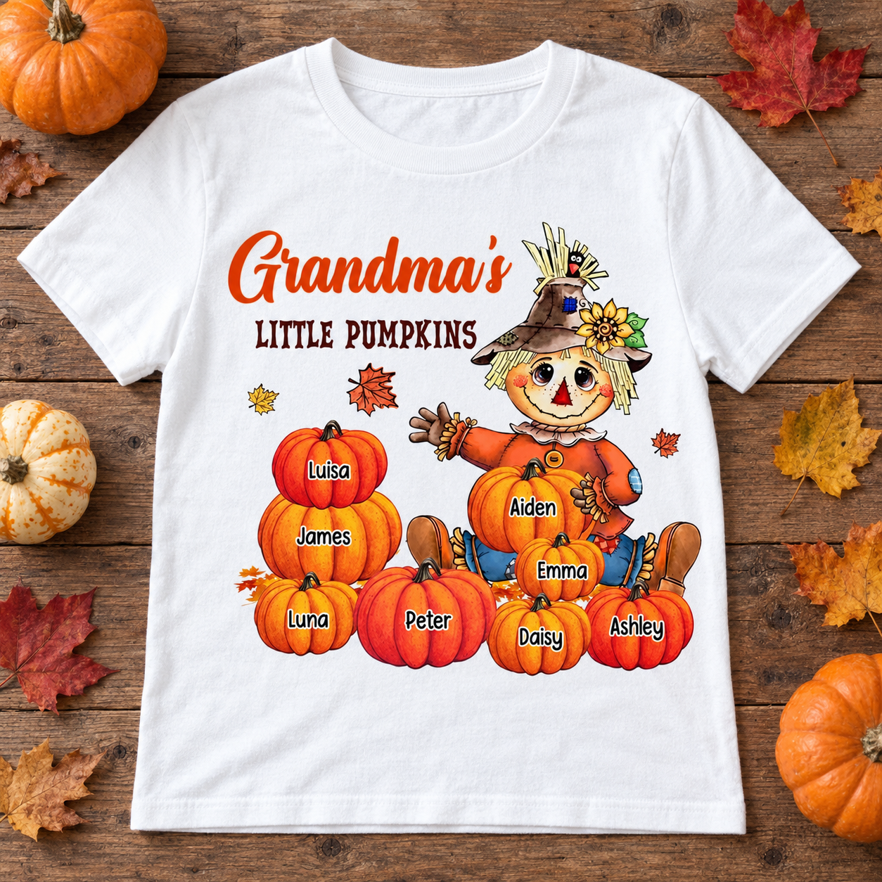 White Grandma's Little Pumpkins personalized scarecrow t-shirt flat lay with pumpkins and fall leaves