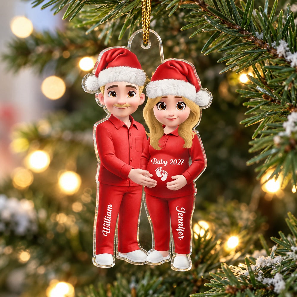Personalized expecting parents acrylic ornament hanging on a Christmas tree branch with warm lights