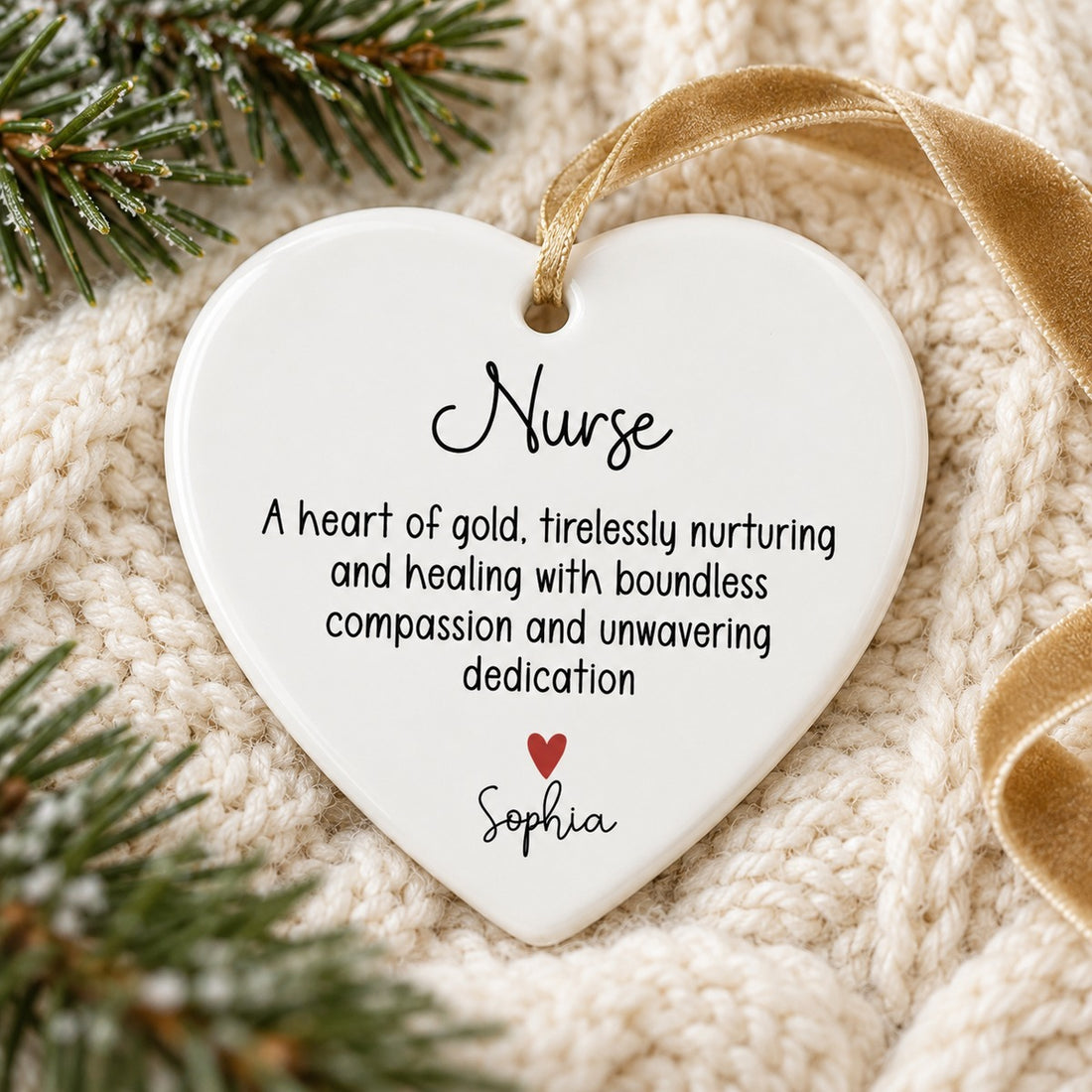 Personalized nurse ceramic heart ornament lying flat on a cream knit blanket with pine sprigs