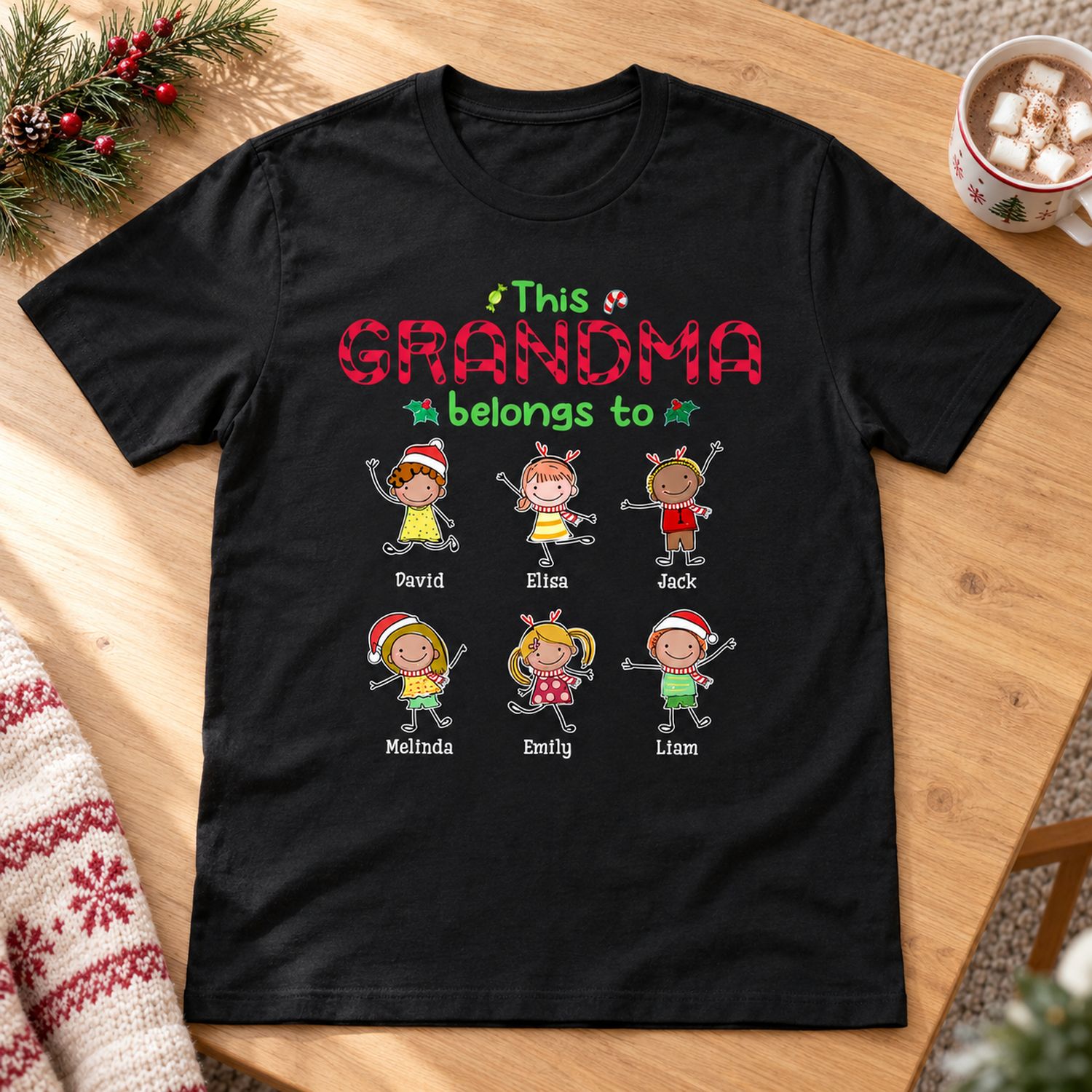 Personalized Christmas Grandma t-shirt laid flat on wooden table with holiday pine decor