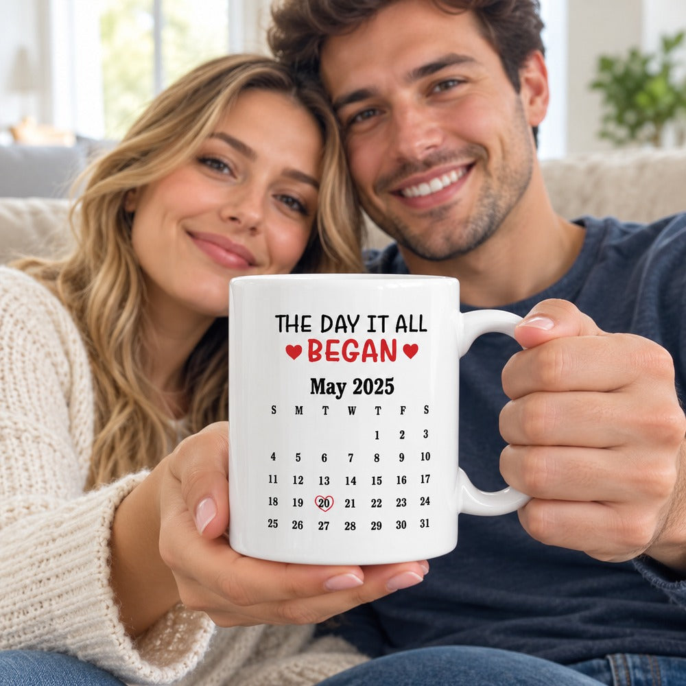 Happy couple holding their personalized The Day It All Began calendar mug on sofa