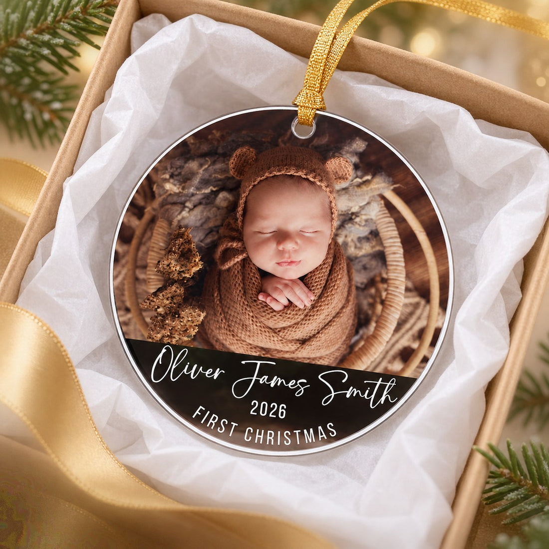 Personalized baby first Christmas circle acrylic ornament nestled in a gift box with tissue paper