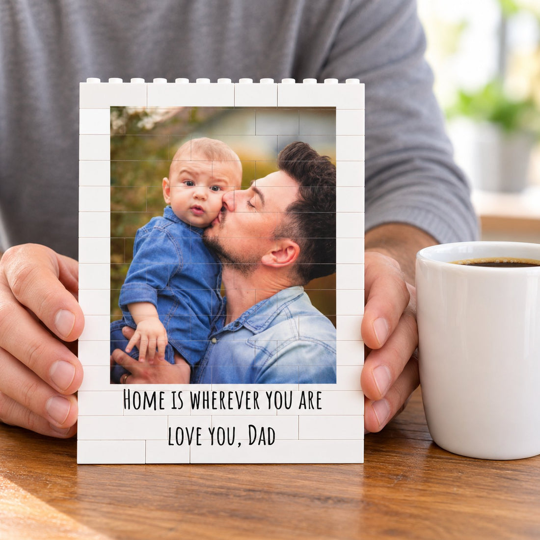 Hands holding the custom photo building brick block next to a coffee mug for size