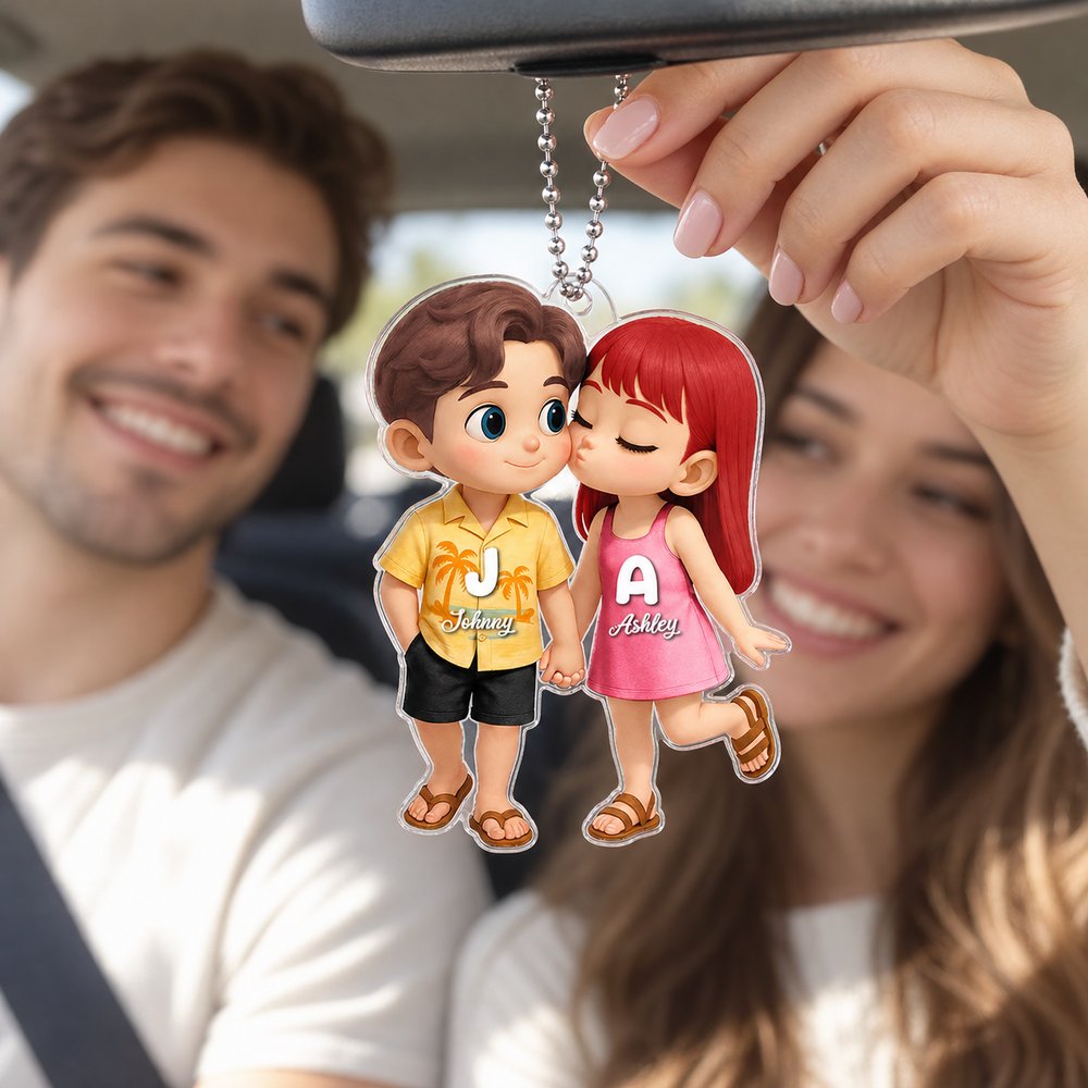Young couple holding personalized cartoon couple acrylic car hanger inside bright car