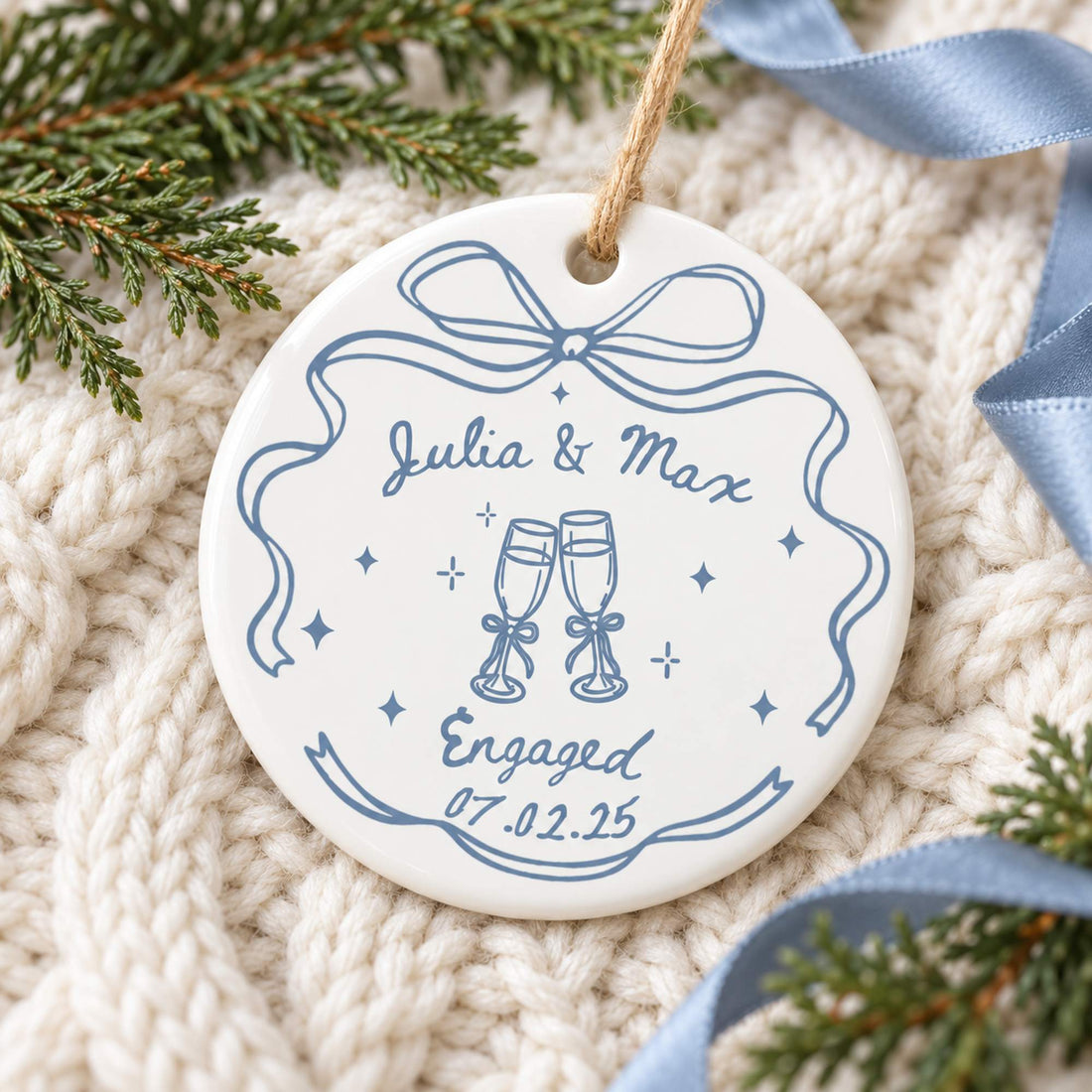 Engaged couple ceramic ornament lying flat on cozy cream knit blanket with greenery