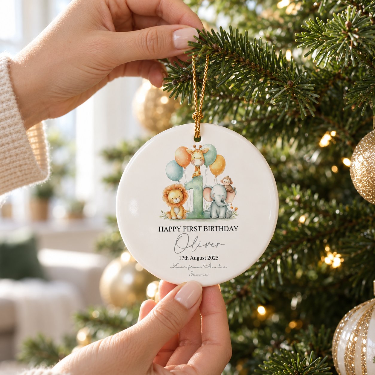 Personalized first birthday safari ceramic ornament being hung on a Christmas tree branch