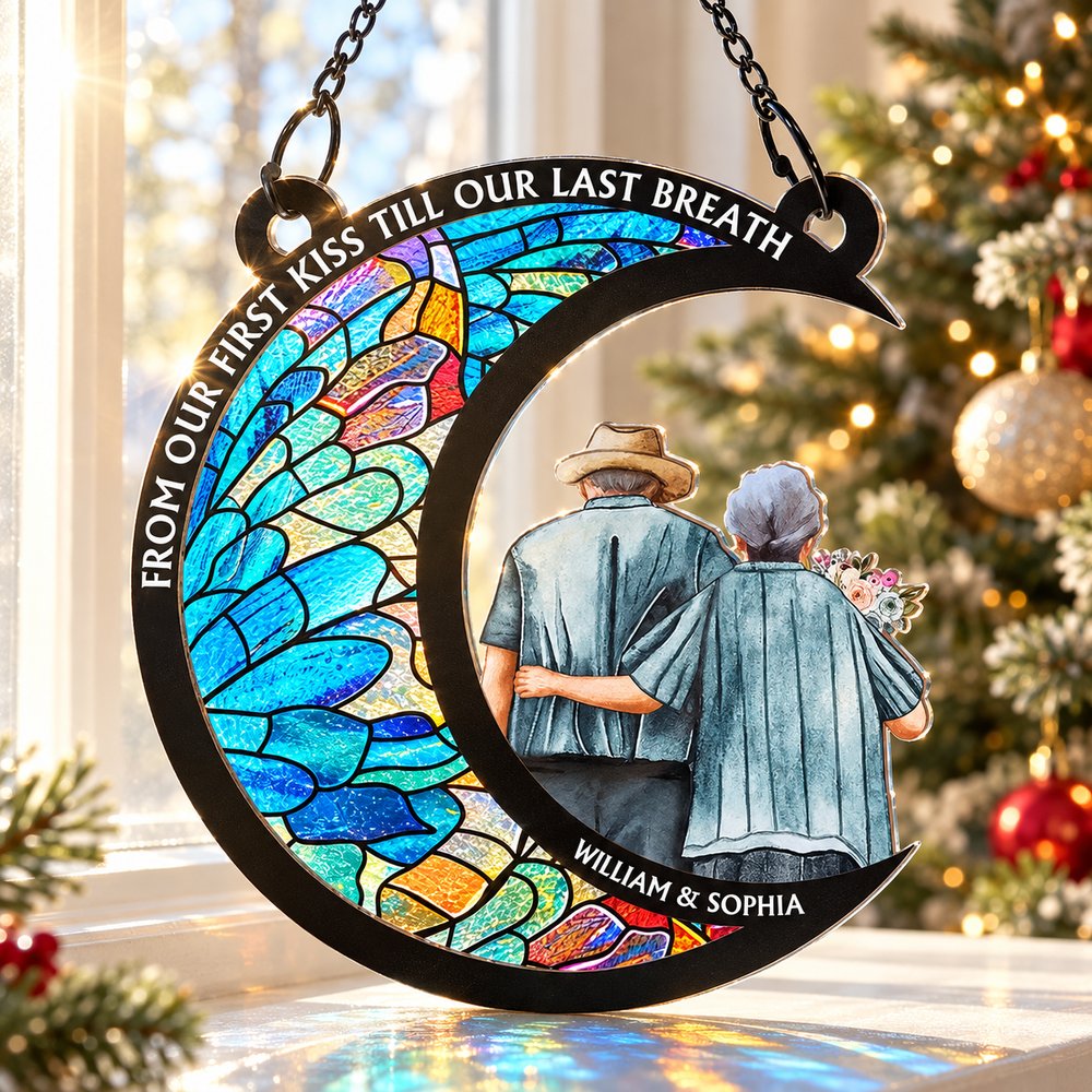 Personalized couple crescent moon suncatcher hanging in a bright holiday window near a Christmas tree