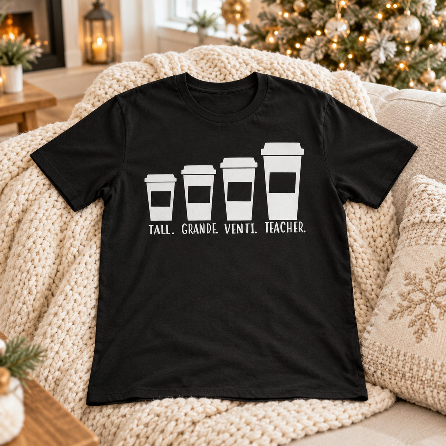 Black funny teacher coffee t-shirt laid on a cozy sofa near a Christmas tree