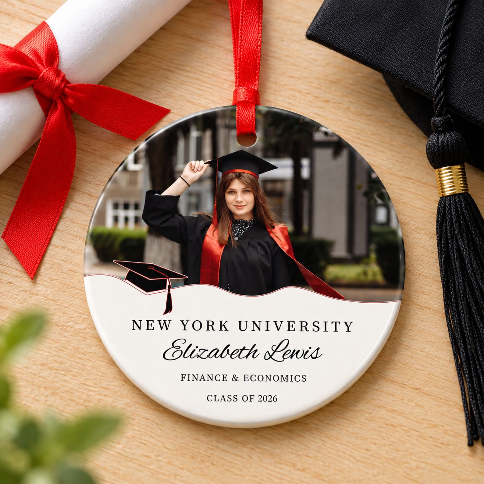 Personalized 3 inch ceramic graduation ornament next to diploma and tassel for scale