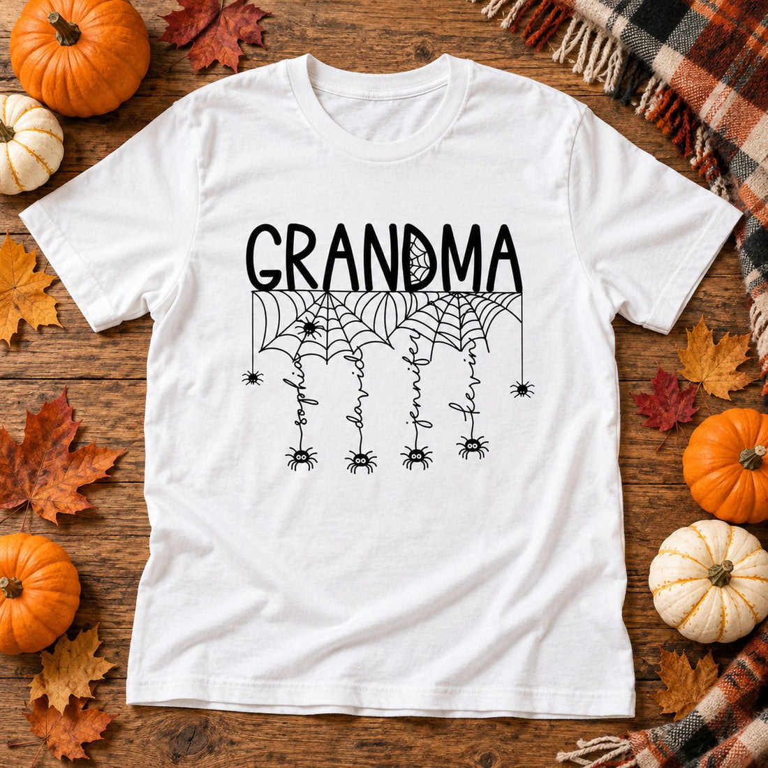 Personalized Grandma Halloween spooky spiders t-shirt laid flat with pumpkins and fall leaves