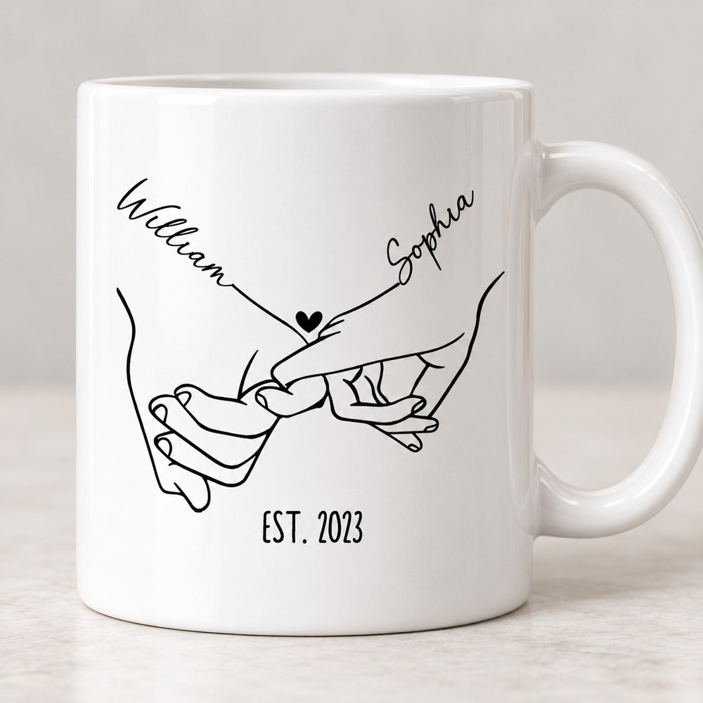 Close-up detail of the black line art holding hands and personalized names on the white ceramic mug