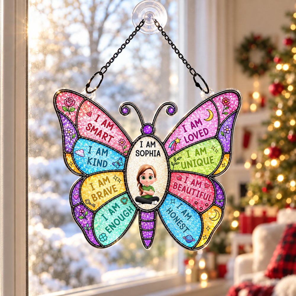 Personalized butterfly suncatcher ornament hanging in window with blurred Christmas tree in background
