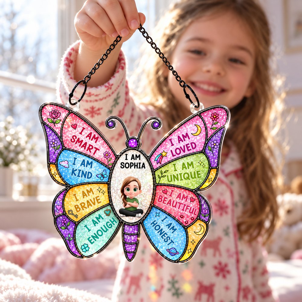 Young girl holding personalized I Am Smart Kind Brave butterfly suncatcher ornament near bright window