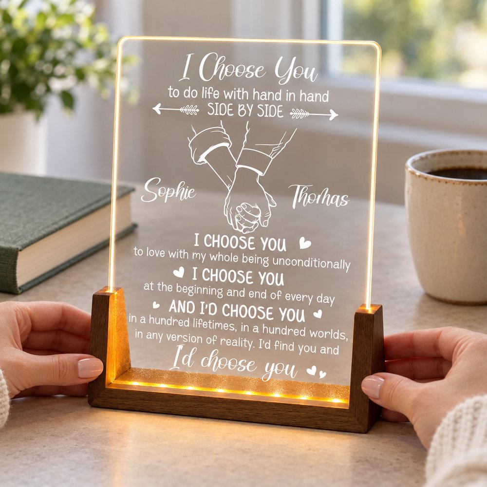 Hands holding 6.5x8.3 inch personalized couple LED plaque next to mug for size