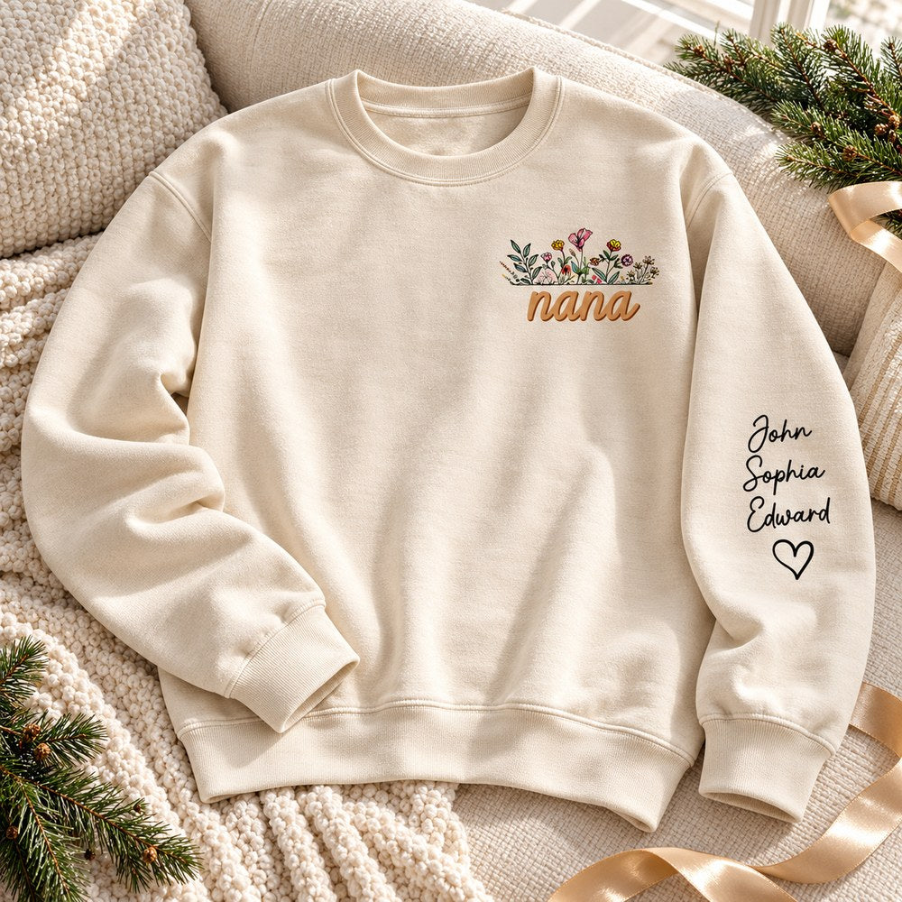 Personalized Nana sleeve printed sweatshirt laid on sofa with holiday greenery