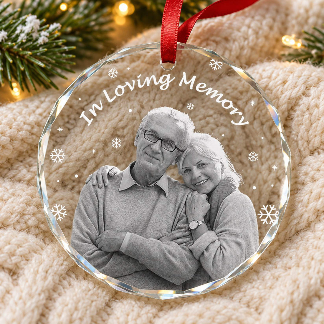 Custom Photo In Loving Memory circle glass ornament lying flat on a cozy cream knit blanket with pine branches
