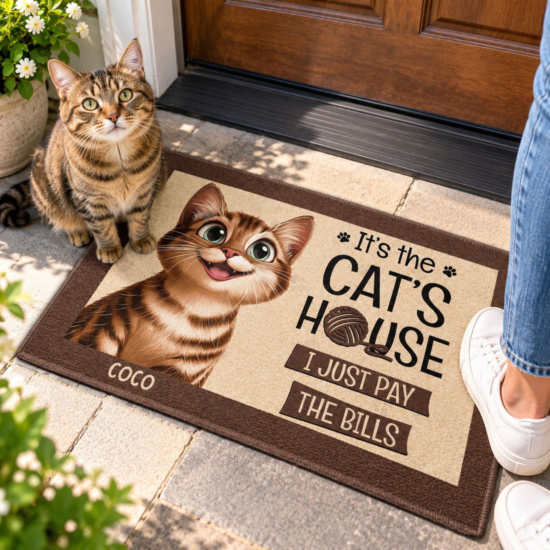 Tabby cat sitting on the It's The Cat's House personalized doormat at a front door