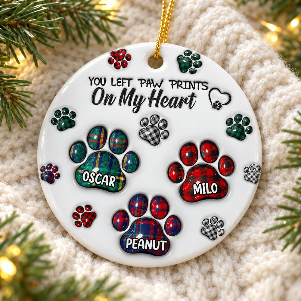 Memorial pet paw prints ceramic ornament lying on cozy cream knit blanket with pine sprigs