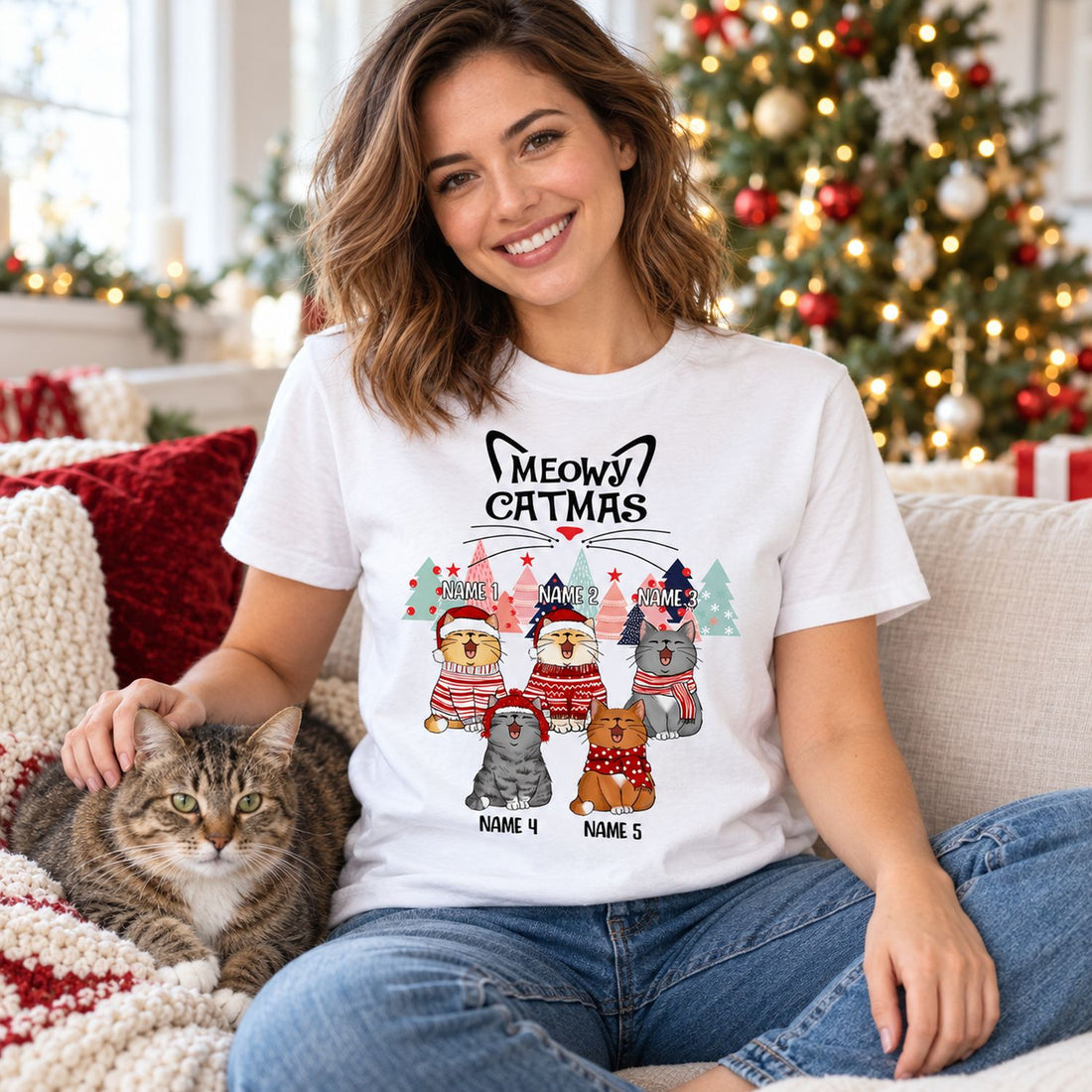 Woman wearing Meowy Catmas personalized cat Christmas t-shirt on sofa with her cat near Christmas tree