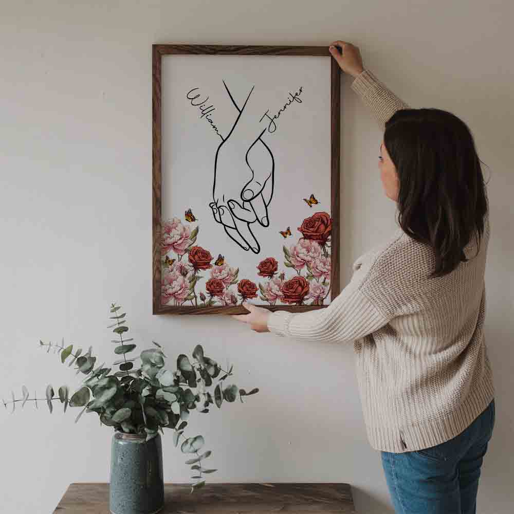Personalized I Love You Couple Hand Print Birth Flower poster, a woman hanging the framed print on a wall