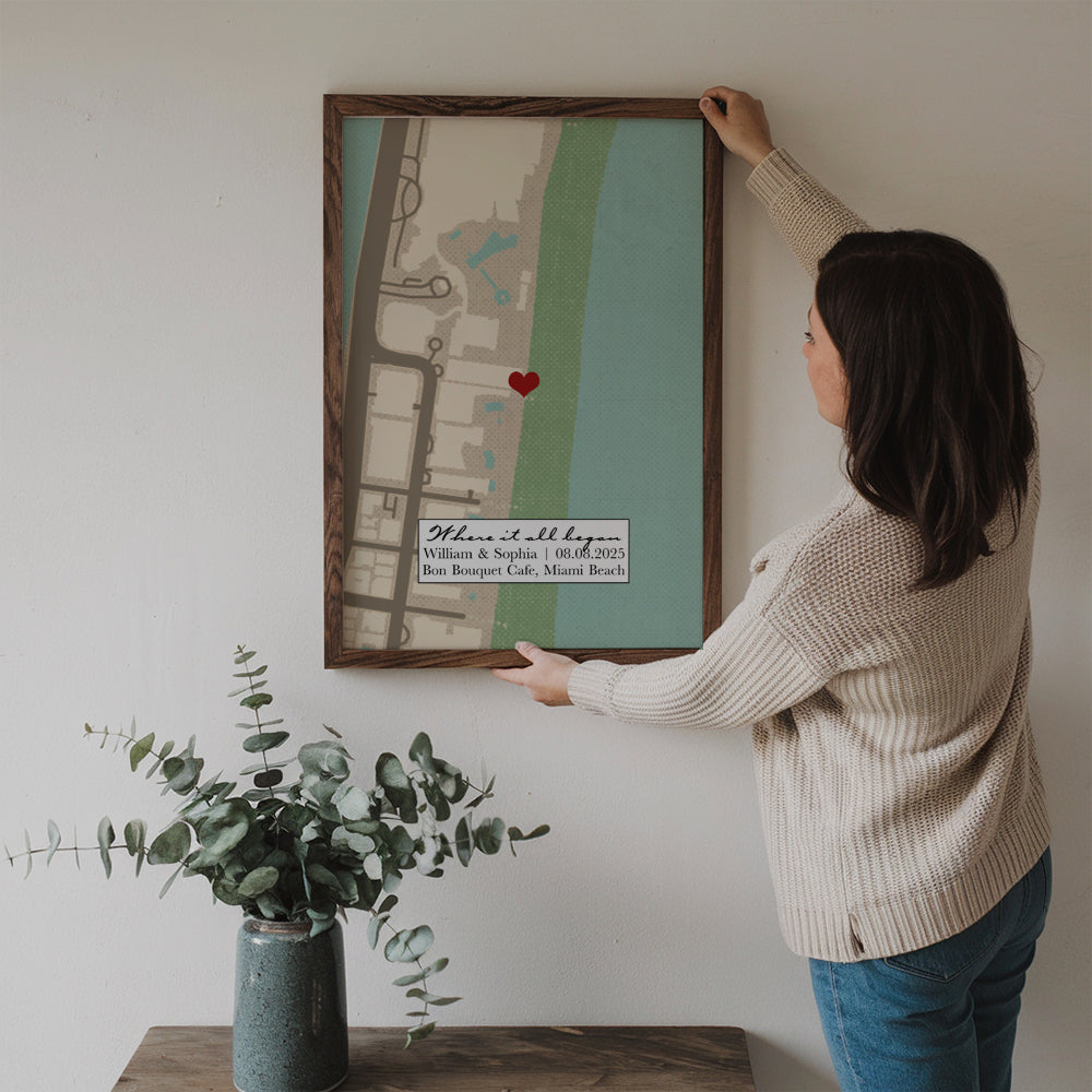 Personalized Where It All Began Where We Met Map Couple poster, a woman hanging the framed print on a wall