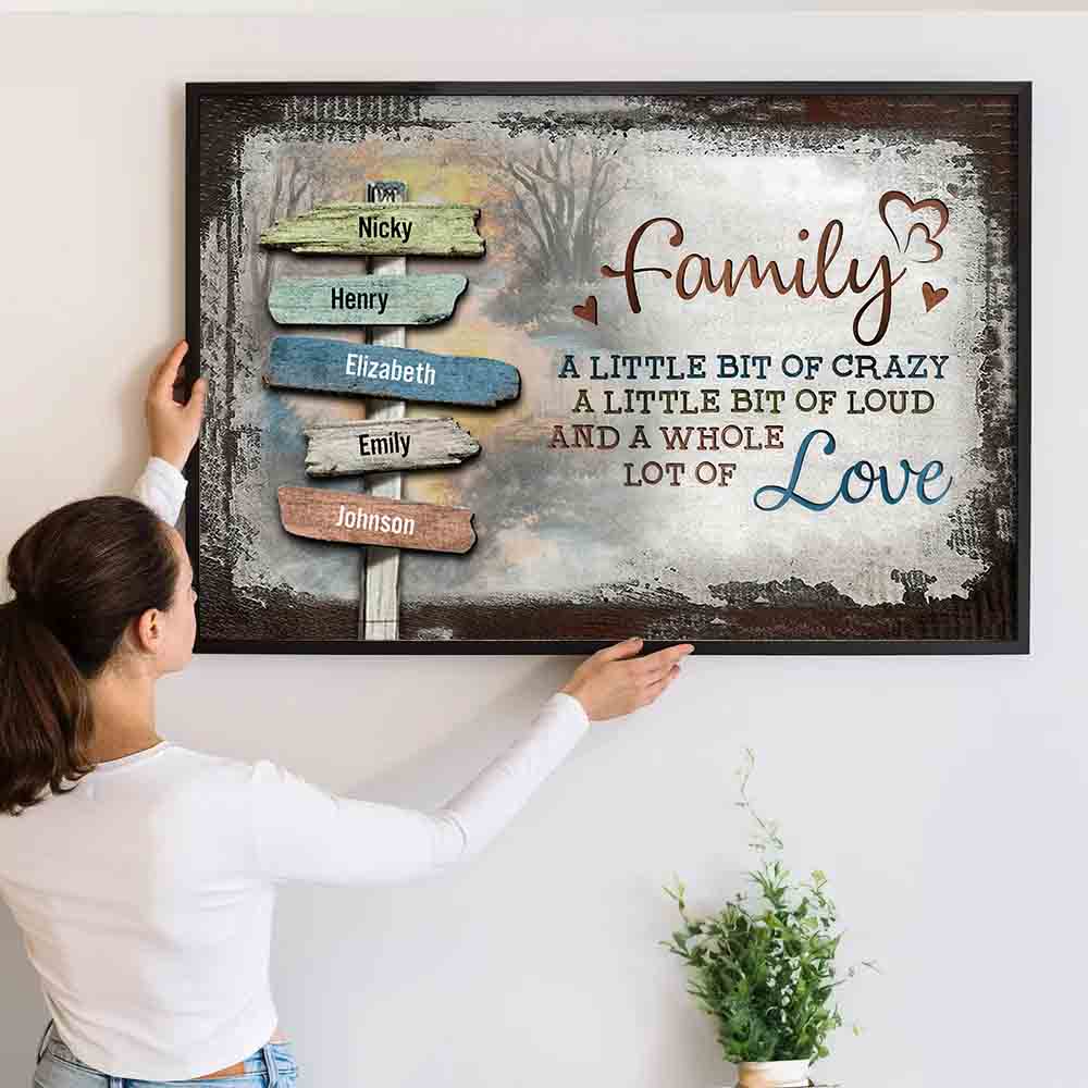 Family sign-post canvas "A little bit of crazy, a whole lot of love", a woman hanging the framed print on a wall