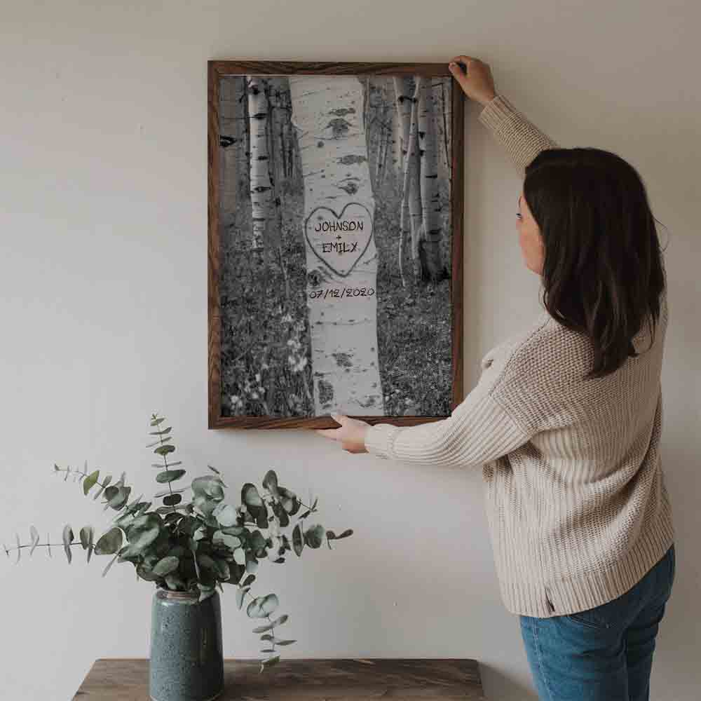 Personalized Couple Names Tree Carving poster, a woman hanging the framed print on a wall