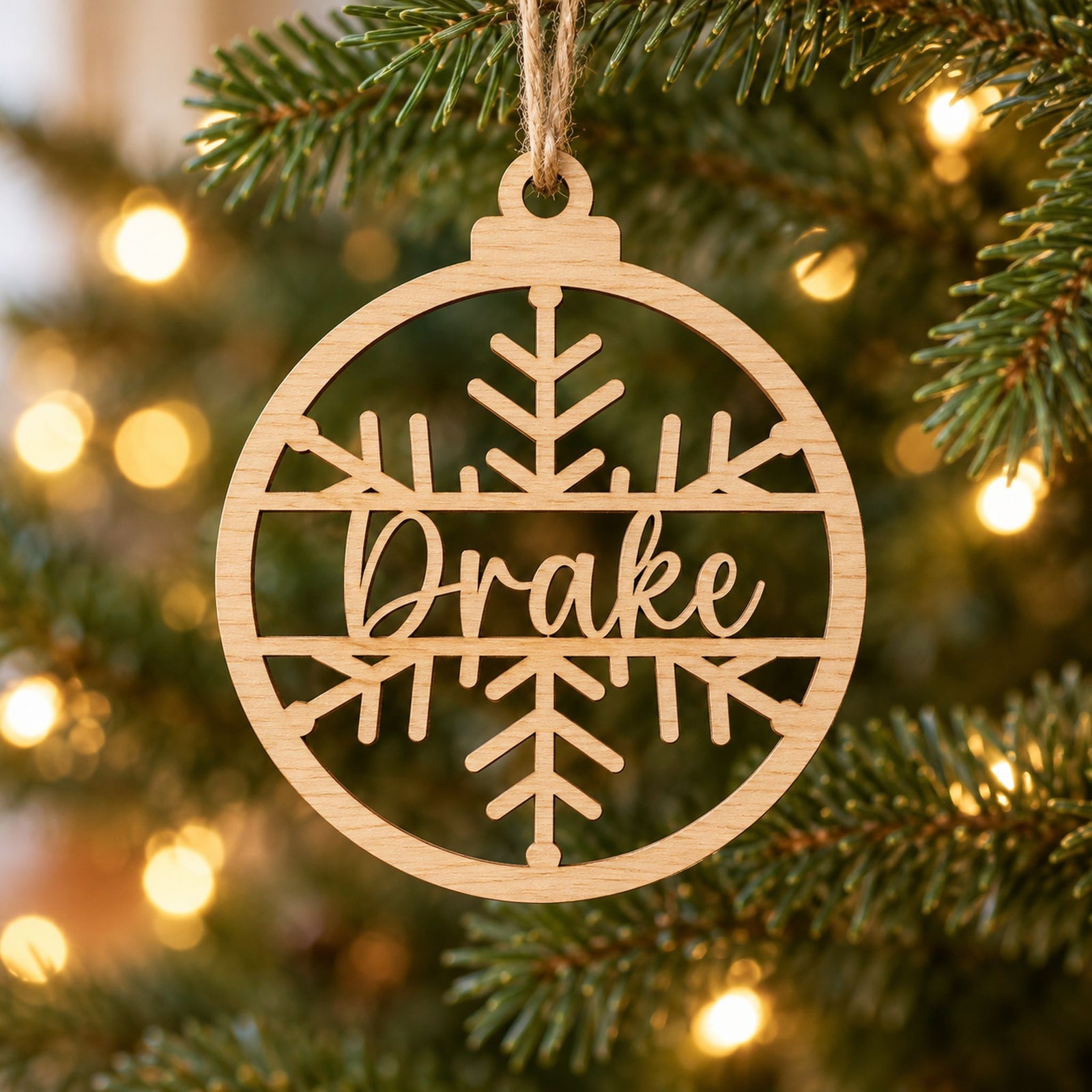Personalized name laser-cut wood ornament hanging on a green Christmas tree branch
