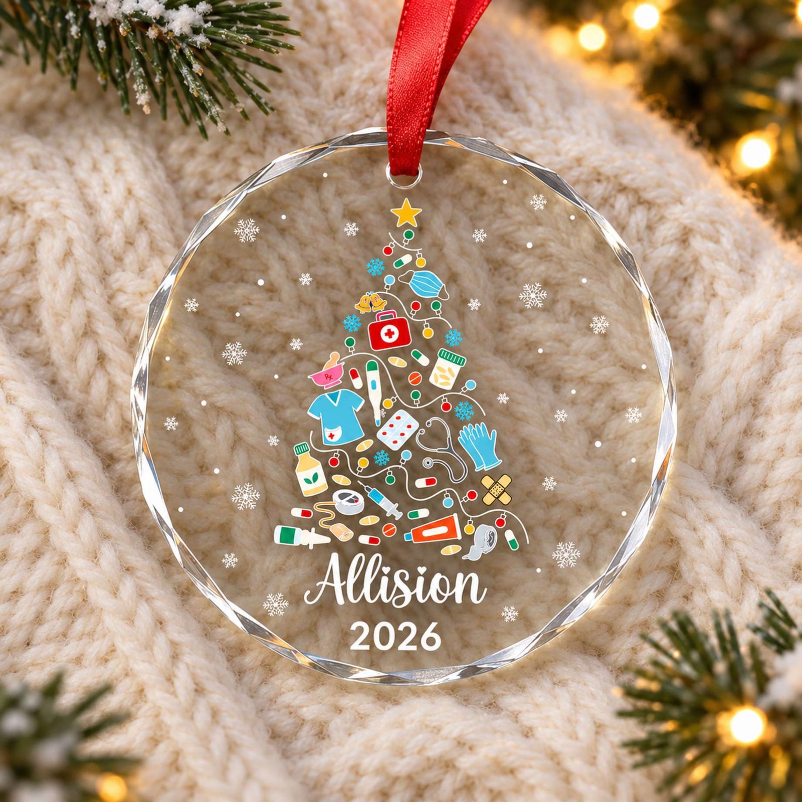 Nurse Christmas tree circle glass ornament lying on a cozy cream knit blanket with pine greenery